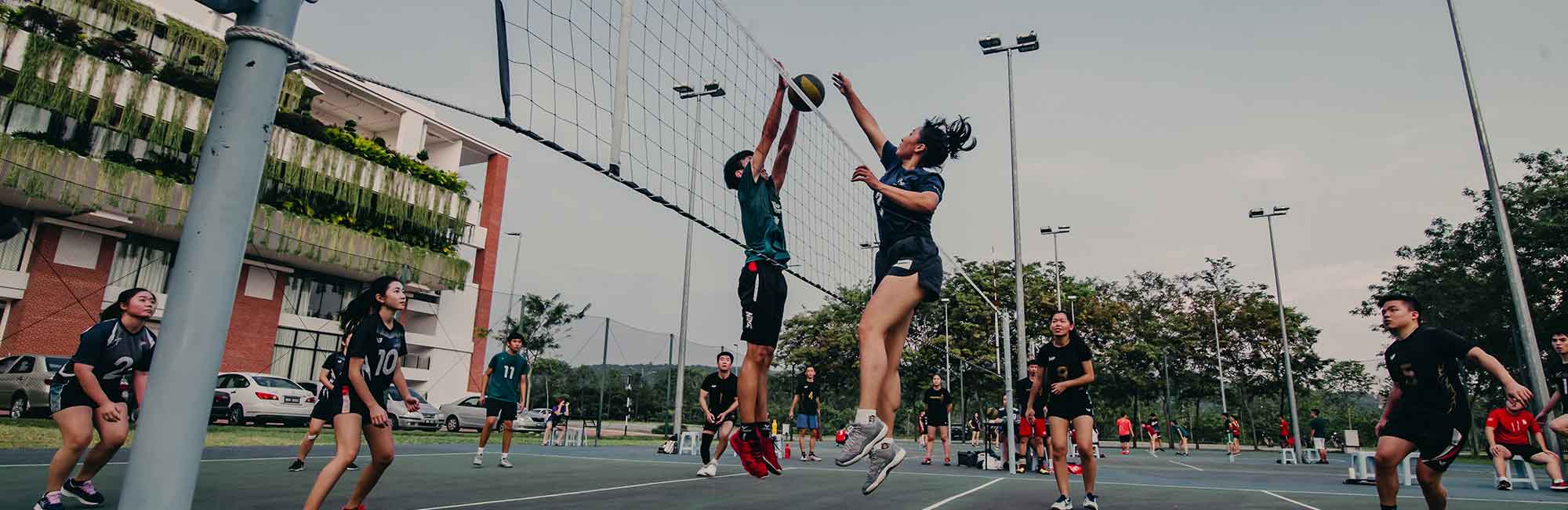 student grający w siatkówkę na boisku uniwersyteckim