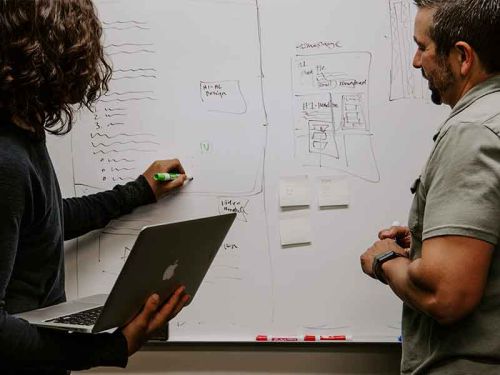 kobieta z mężczyzną robią notatki na tablicy