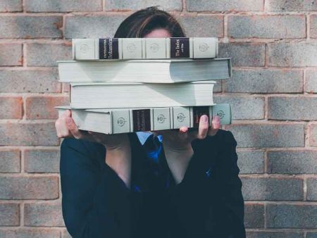 uczennica trzyma książki zakrywające jej twarz