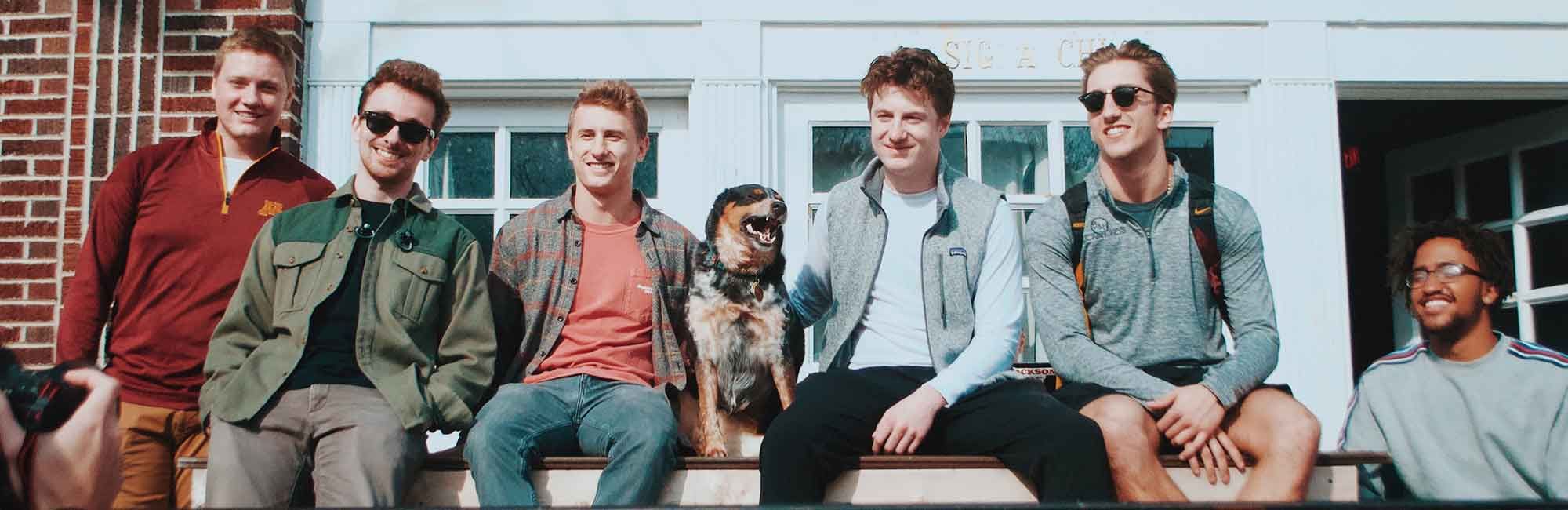 uczniowie siadają na ścianie przed klubem studenckim i robią sobie zdjęcie