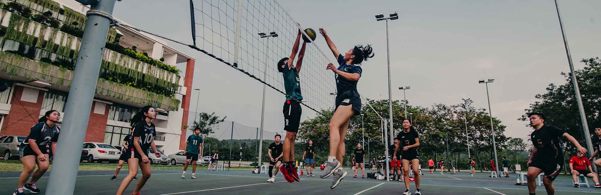 student grający w siatkówkę na boisku uniwersyteckim